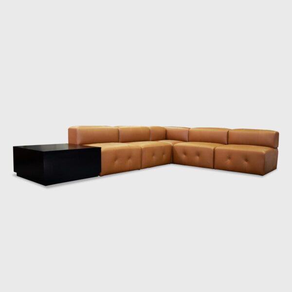 The Bryant Banquette from Jamie Stern features a rounded back, tight seat with button tufting, and wood corner tables.