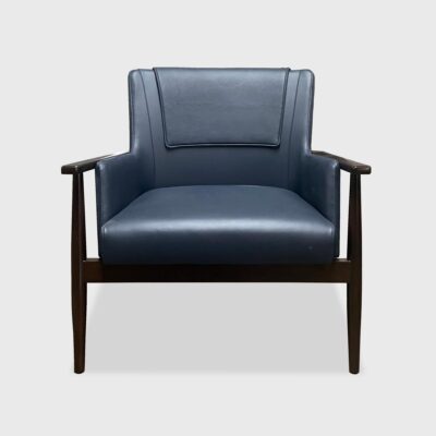 The Landon Lounge Chair from Jamie Stern features a tight upholstered back with a head rest cover, an exposed wood frame and round tapered legs.