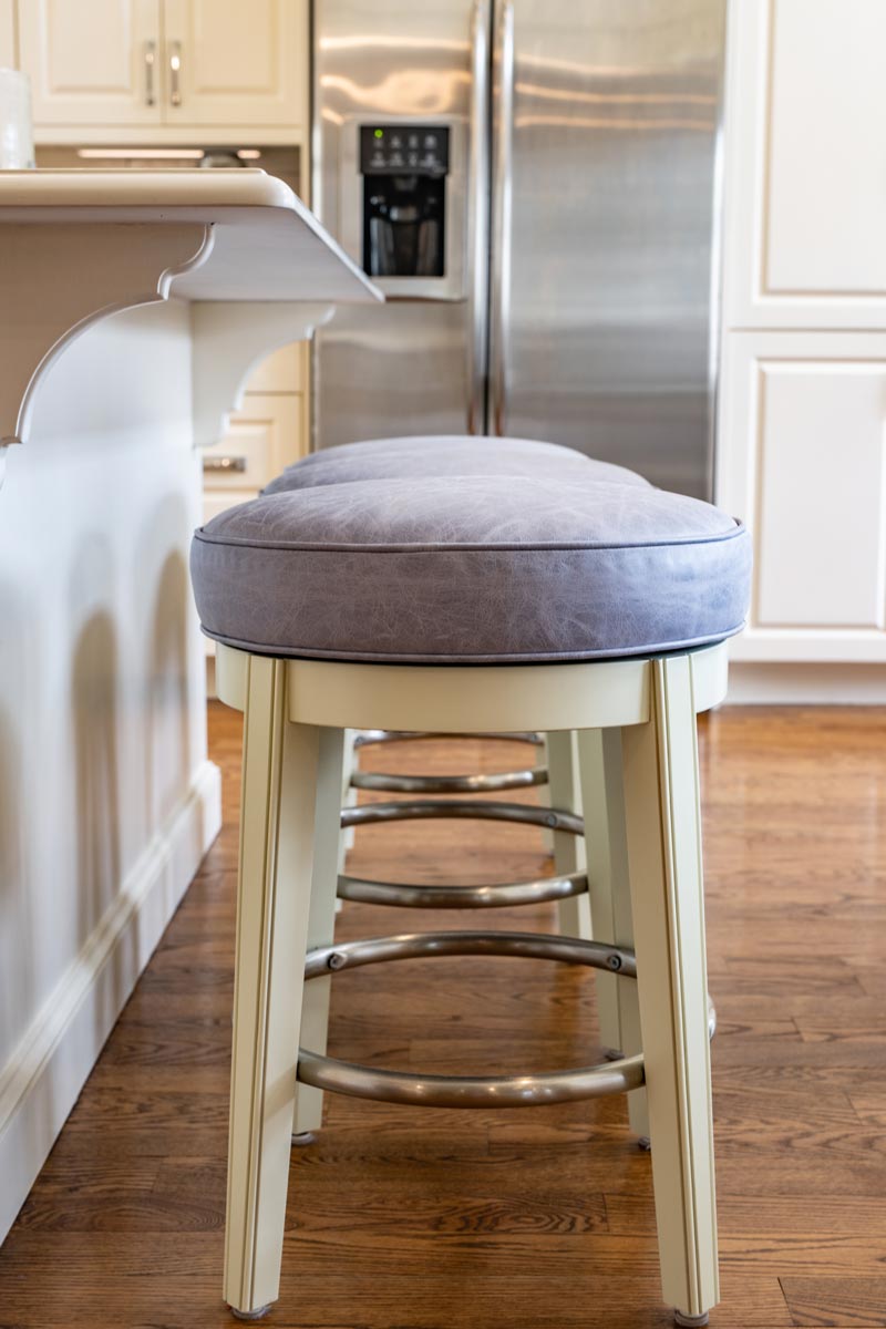 Distressed grey leather upholstered barstools by Jamie Stern