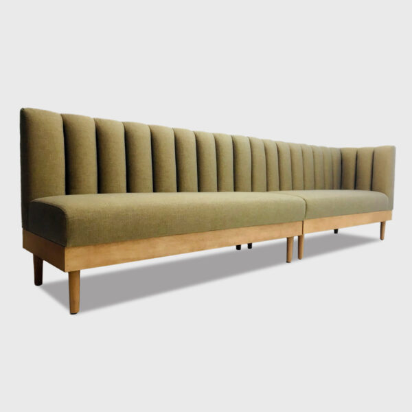 The Tabago Banquette features a tight upholstered back with vertical channels, an exposed wood apron and tapered wood legs.